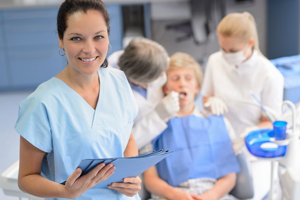 Dentist smiling as dental team works with patient