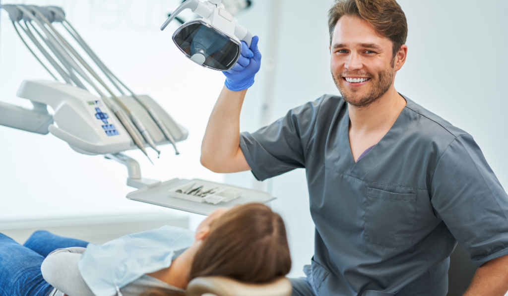 A smiling dentist in his office sitting above a patient