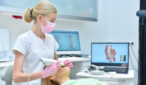 A female dental professional using an intraoral scanner to take a digital impression of a patient's mouth
